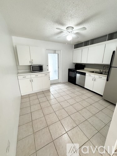 A kitchen with white cabinets and a tile floor.