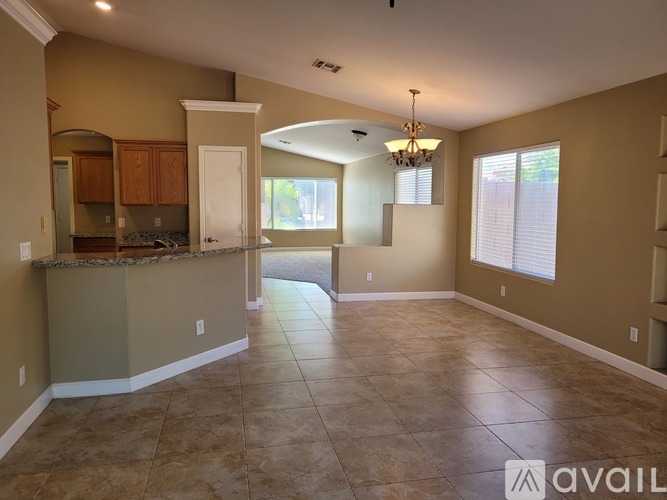 A spacious living room with a kitchen area in the background.