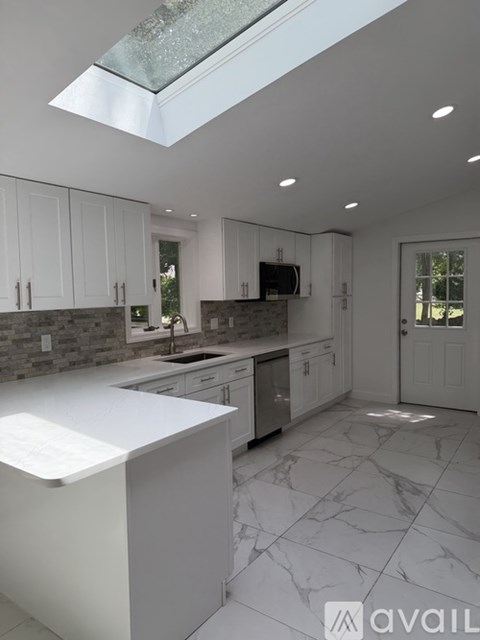 A modern kitchen with white cabinets and marble flooring.