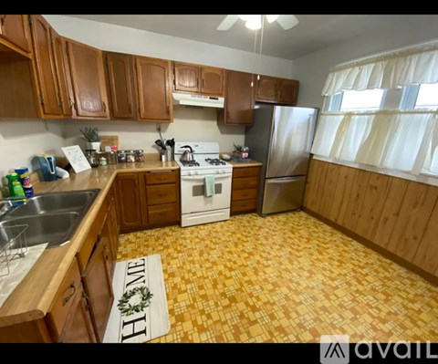 A kitchen with wooden cabinets and a yellow floor mat that says "HOME".