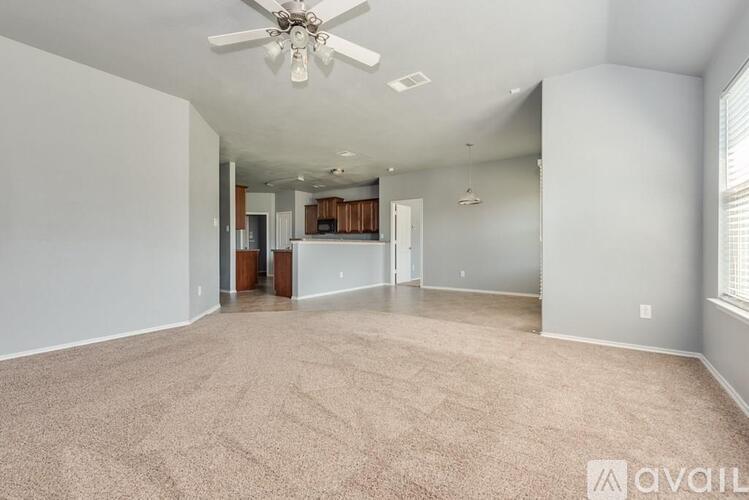 A spacious living room with a carpeted floor and a ceiling fan.
