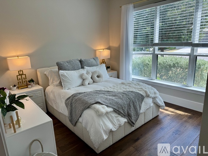 A bedroom with a large bed and a window with blinds.