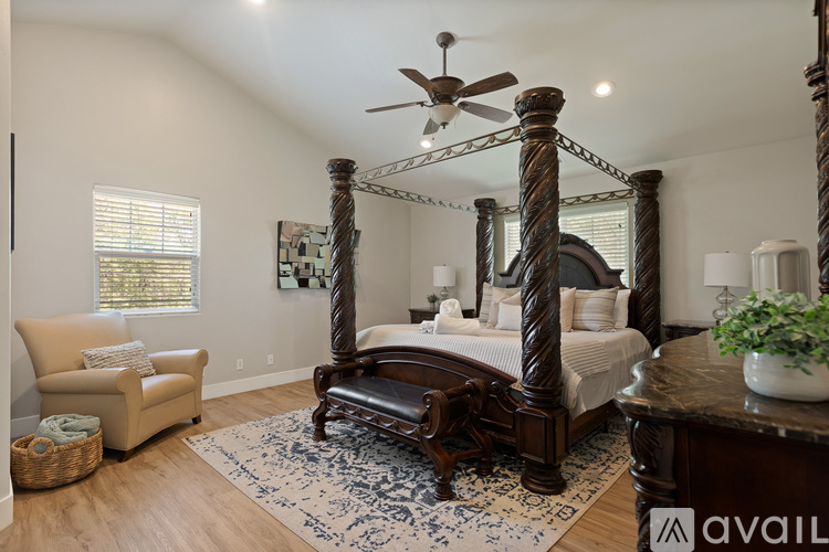 A bedroom with a four poster bed and a rug on the floor.