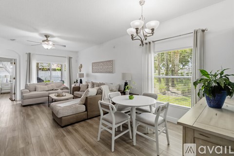 A living room with a white ceiling fan and a white dining table with chairs.