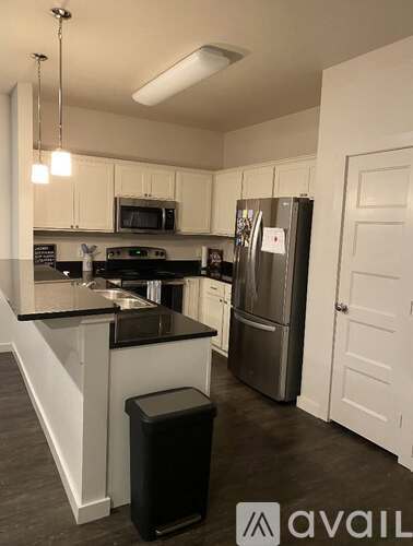 A kitchen with white cabinets and a black counter.