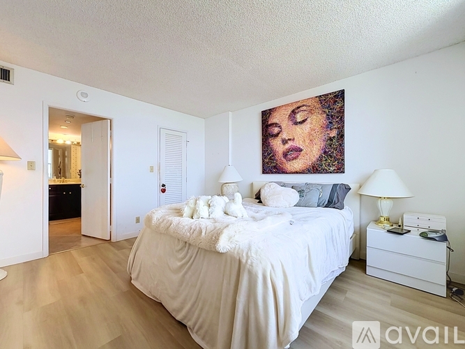 A bedroom with a large bed and a painting on the wall.