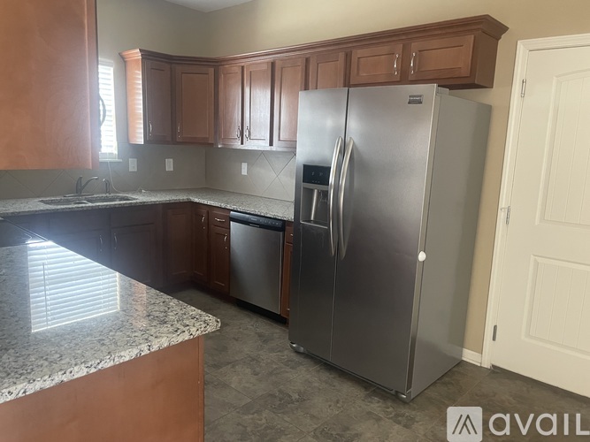 A kitchen with a granite counter top and a stainless steel refrigerator.
