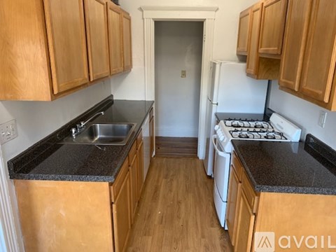 A kitchen with wooden cabinets and black countertops.