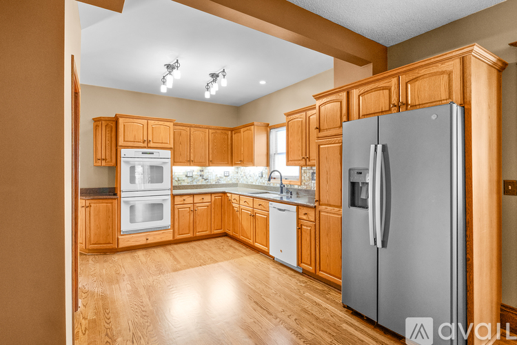 A kitchen with wooden cabinets and a grey refrigerator.