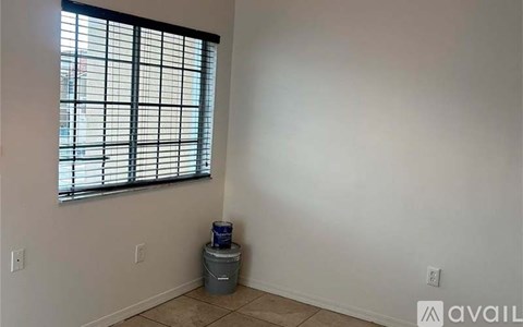 A room with a window and a trash can.