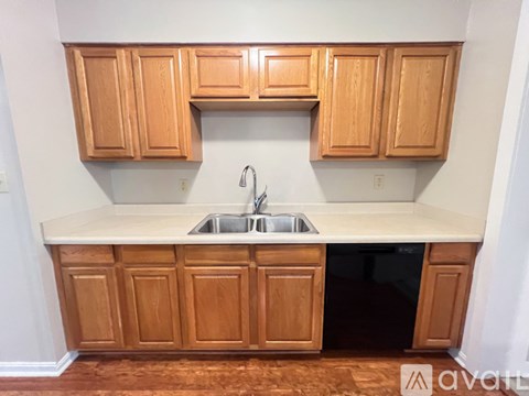 A kitchen with wooden cabinets and a black dishwasher.