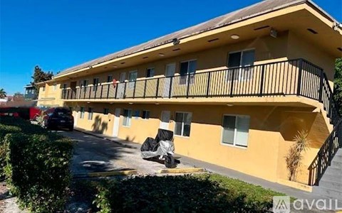 A yellow building with a balcony and a car parked in front.