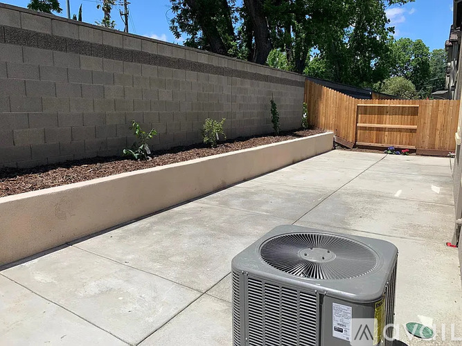 A concrete patio with a fan and a wooden fence.