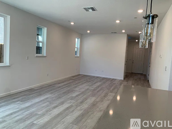 A spacious room with wooden flooring and a chandelier hanging from the ceiling.