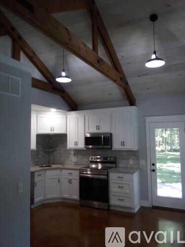 A kitchen with white cabinets and a wooden ceiling.