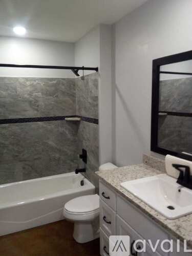 A bathroom with a tub, toilet, sink, and mirror.