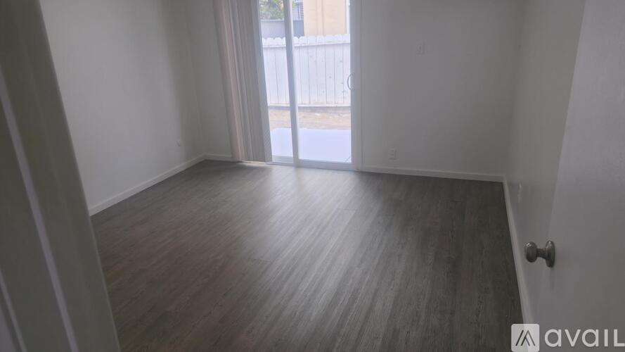 A room with wooden flooring and a sliding glass door leading outside.