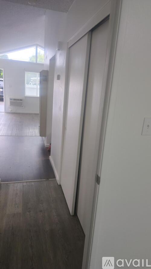 A hallway with a white door and a window.