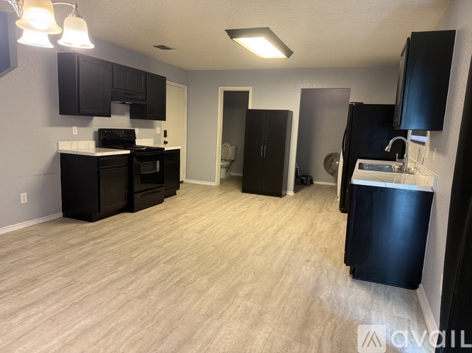 A kitchen with black cabinets and a wooden floor.
