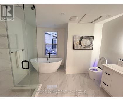A bathroom with a glass shower door, a white bathtub, a toilet, and a sink.