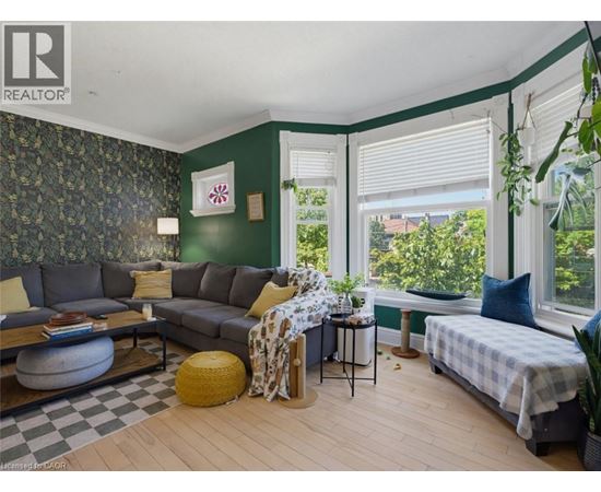 A living room with a grey couch and a green wallpaper.