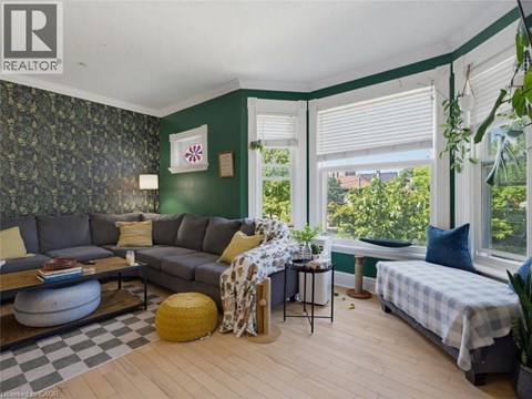A living room with a grey couch and a green wallpaper.