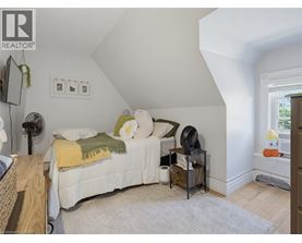A bedroom with a bed, nightstand, and a fan.