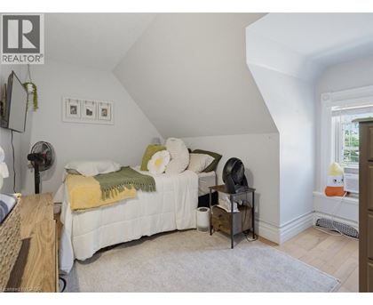 A bedroom with a bed, nightstand, and a fan.