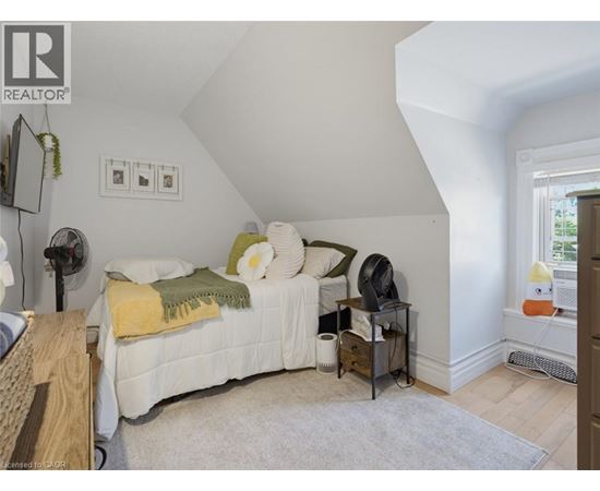 A bedroom with a bed, nightstand, and a fan.