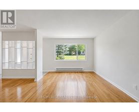A room with wooden floors and a large window showing trees outside.
