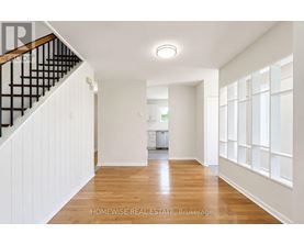 A spacious hallway with wooden floors and white walls.