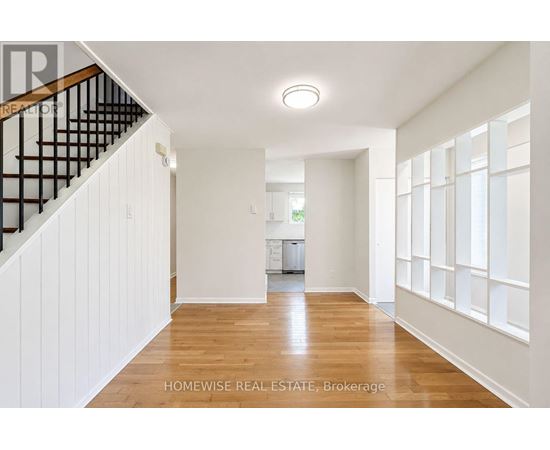A spacious hallway with wooden floors and white walls.
