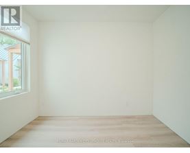 A white room with a window and a wooden floor.