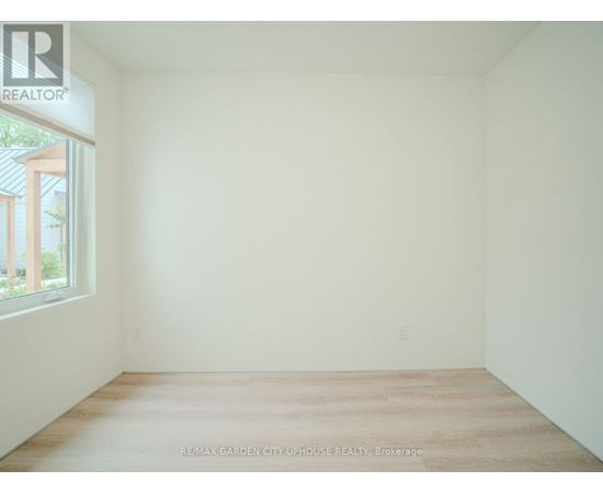 A white room with a window and a wooden floor.