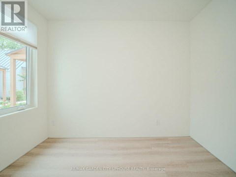 A white room with a window and a wooden floor.