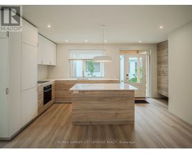 A modern kitchen with wooden floors and white cabinets.