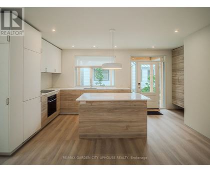 A modern kitchen with wooden floors and white cabinets.