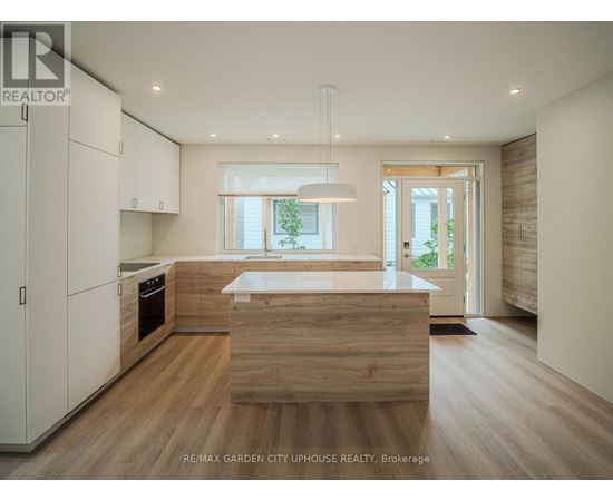 A modern kitchen with wooden floors and white cabinets.
