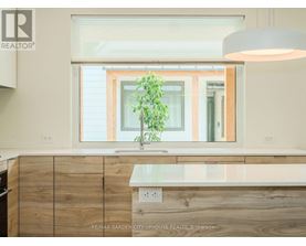 A modern kitchen with wooden cabinets and a large window.