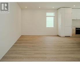 A spacious room with wooden flooring and white walls.