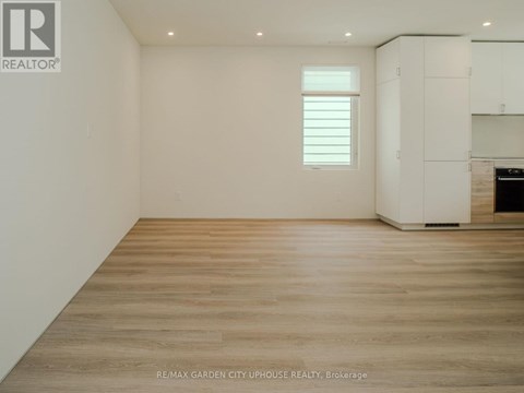 A spacious room with wooden flooring and white walls.