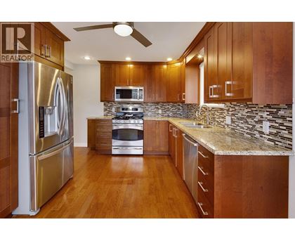 A kitchen with wooden cabinets and a stainless steel refrigerator.