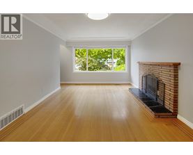 A large, empty room with a fireplace and a window.