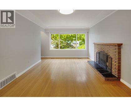 A large, empty room with a fireplace and a window.
