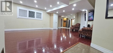 A spacious room with a polished floor and a large window.