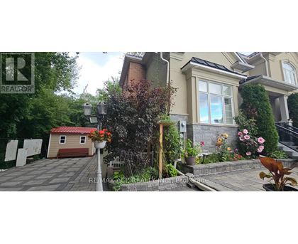 A house with a red garage door is surrounded by greenery and plants.