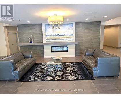A living room with a grey couch and a black and white rug.