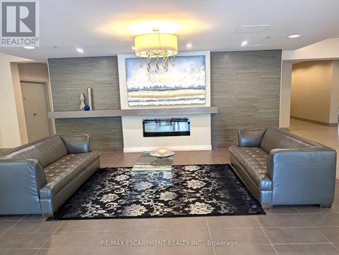 A living room with a grey couch and a black and white rug.