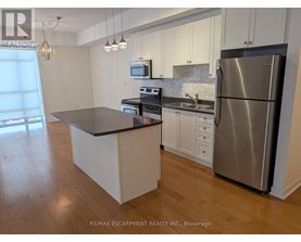 A kitchen with a stainless steel refrigerator and a black countertop.