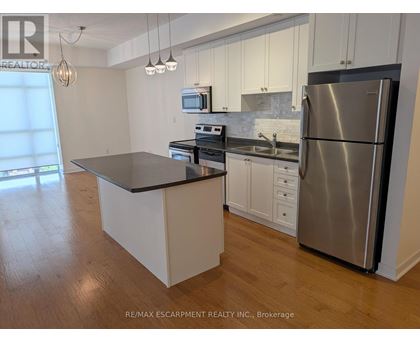 A kitchen with a stainless steel refrigerator and a black countertop.
